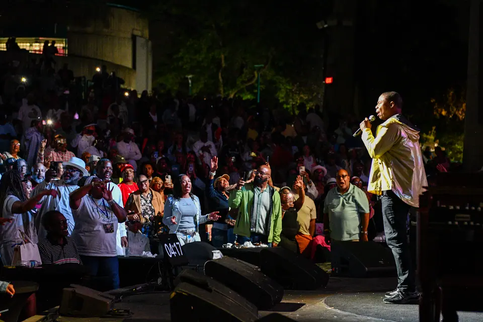 Doug E. Fresh stands at the edge of the stage facing a packed, cheering amphitheatre crowd